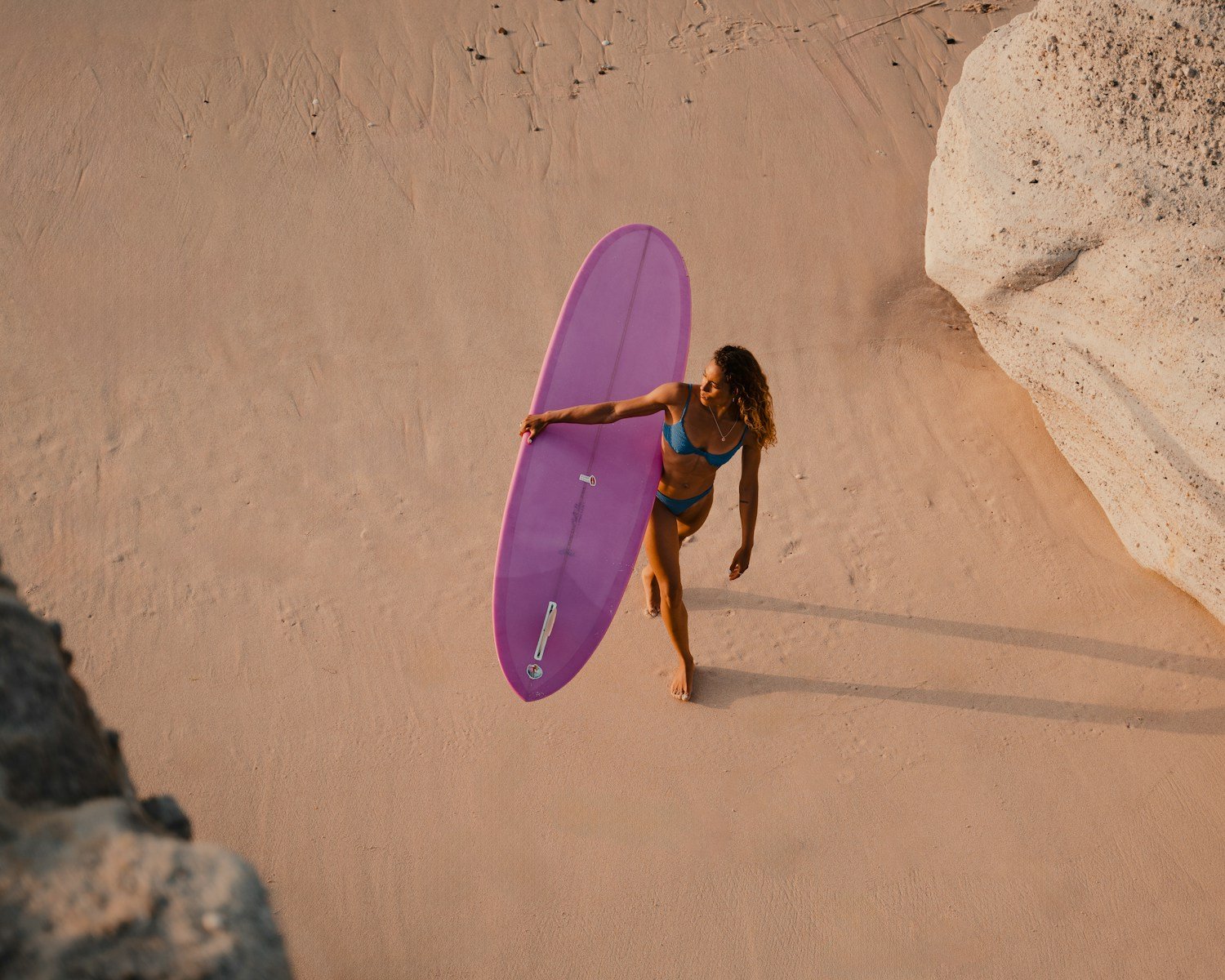 A woman in a bikini holding a purple surfboard